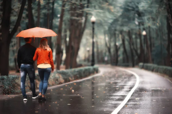 秋の公園の雨 若い25歳のカップル男と女は湿った雨の中で傘の下を歩く 10月の恋人を歩く — ストック写真