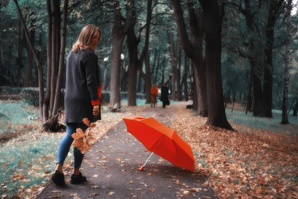 autumn landscape in the park girl with a red umbrella / concept autumn weather raining, a young woman under an umbrella