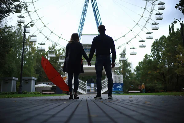 two people under an umbrella / a man and a woman are walking in a park with an umbrella, walking in the fall in the rain, an autumn umbrella