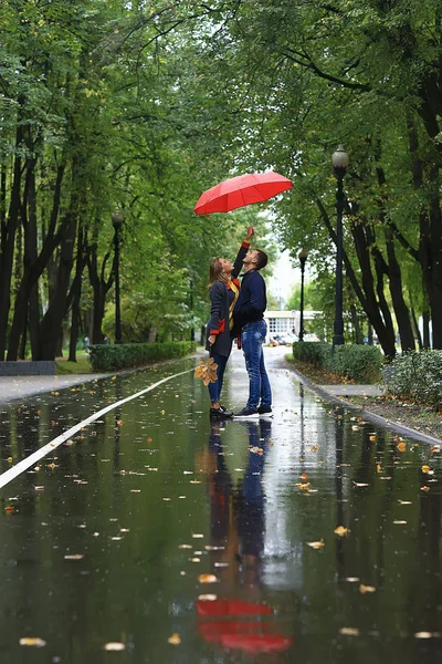 bir şemsiye altında iki kişi/bir erkek ve bir kadın bir şemsiye ile bir parkta yürüyüş, yağmur sonbaharda yürüyüş, bir sonbahar şemsiyesi