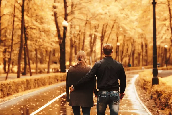 秋の公園の太陽光線 愛のカップル 若い男性と女性が歩いている 日当たりの良い公園の秋の眺め 太陽の光 暖かい秋の背景 — ストック写真