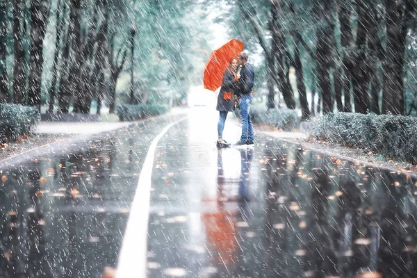 Sonbahar parkında yağmur/genç 25 yaşında çift adam ve kadın ıslak yağmurlu havalarda bir şemsiye altında yürümek, Ekim severler yürümek