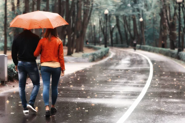 秋の公園の雨 若い25歳のカップル男と女は湿った雨の中で傘の下を歩く 10月の恋人を歩く — ストック写真