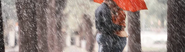 two people under an umbrella / a man and a woman are walking in a park with an umbrella, walking in the fall in the rain, an autumn umbrella