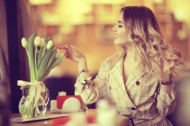 bir masada bir kafede oturan kız/güzel genç model çiçekler bir demet ile poz, mutlu yetişkin kız arkadaşı