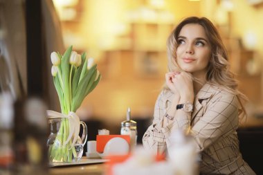 bir masada bir kafede oturan kız/güzel genç model çiçekler bir demet ile poz, mutlu yetişkin kız arkadaşı