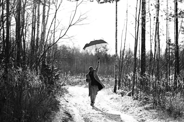 winter walk with an umbrella / man in a coat with an umbrella, walk against the backdrop of the winter landscape, winter view