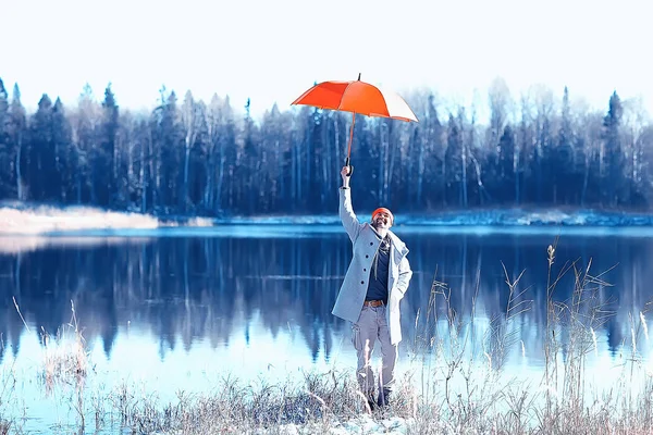 winter walk with an umbrella / man in a coat with an umbrella, walk against the backdrop of the winter landscape, winter view