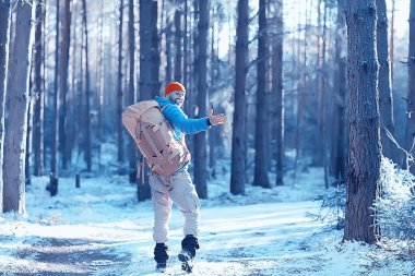 arkadan turist görünümü / bir sırt çantası ile bir adam giden görünümü, kış ormanı geçer