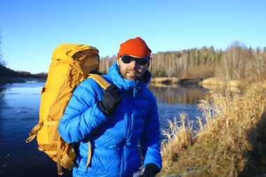 nehir / turist adam tarafından bir sırt çantası ile gezgin kuzey yürüyüşü, kış gezisi