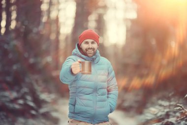 bir kış ormanda gezgin sıcak bir içecek içecekler ve bir fincan tutar