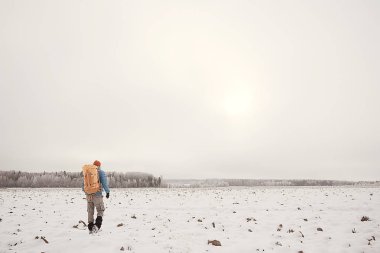 arkadan turist görünümü / bir sırt çantası ile bir adam giden görünümü, kış ormanı geçer