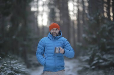 bir kış ormanda gezgin sıcak bir içecek içecekler ve bir fincan tutar