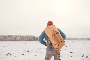 arkadan turist görünümü / bir sırt çantası ile bir adam giden görünümü, kış ormanı geçer