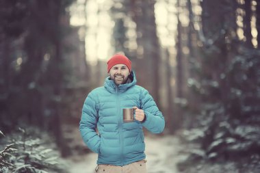 bir kış ormanda gezgin sıcak bir içecek içecekler ve bir fincan tutar