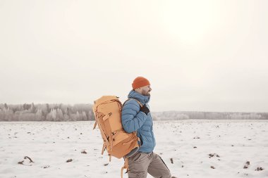 arkadan turist görünümü / bir sırt çantası ile bir adam giden görünümü, kış ormanı geçer