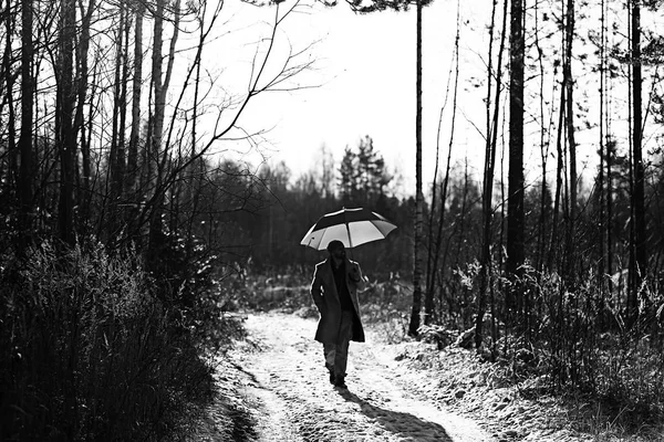 winter walk with an umbrella / man in a coat with an umbrella, walk against the backdrop of the winter landscape, winter view