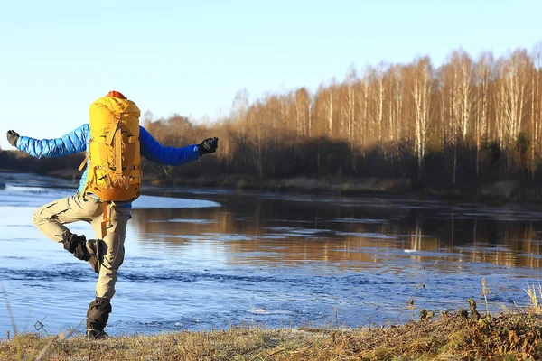 traveler with a backpack by the river / tourist guy on a northern hike, winter trip