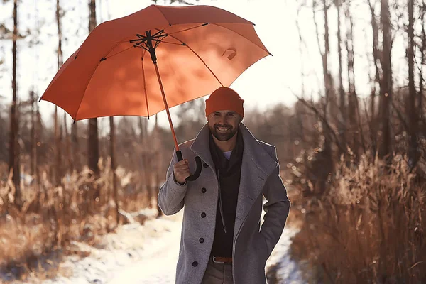 winter walk with an umbrella / man in a coat with an umbrella, walk against the backdrop of the winter landscape, winter view