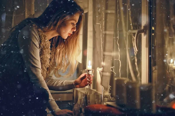Christmas evening girl / beautiful young adult model, dreams and makes wishes at the candles in the New Year\'s Eve
