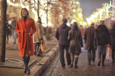 Şehirde kış gecesi. Işıklar. Paltolu yetişkin bir kız. Şehirde yürüyüş.