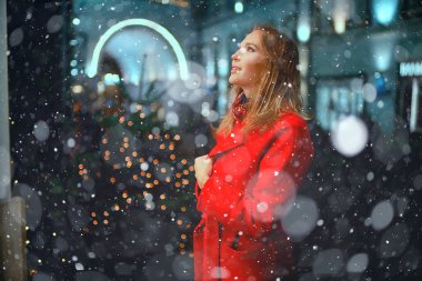 Şehirde Noel yürüyüşü / yetişkin kız bir festival gecesi gece şehirde yürür, şehrin ışıkları yeni yıl