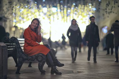 Şehirde Noel yürüyüşü / yetişkin kız bir festival gecesi gece şehirde yürür, şehrin ışıkları yeni yıl