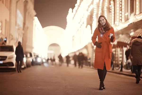 Şehirde kış gecesi. Işıklar. Paltolu yetişkin bir kız. Şehirde yürüyüş.