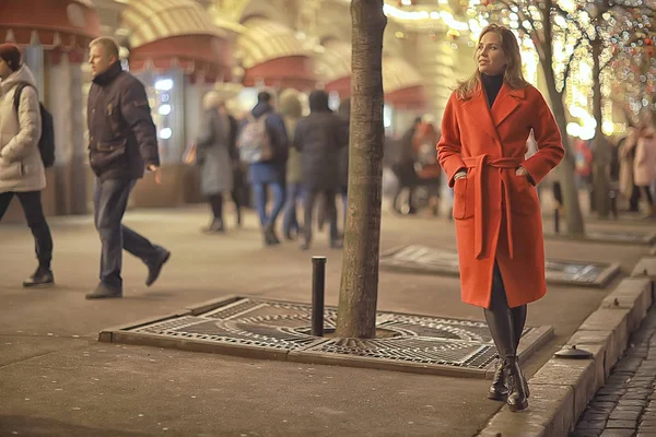 Şehirde kış gecesi. Işıklar. Paltolu yetişkin bir kız. Şehirde yürüyüş.