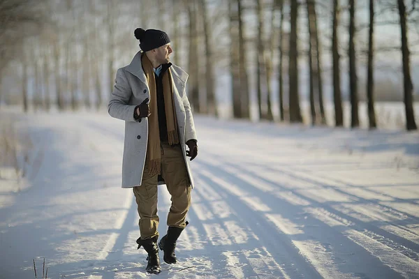 コート 冬のスタイルでファッショナブルな男は 冬の風景 雪の天候 暖かい服を背景に歩きます — ストック写真