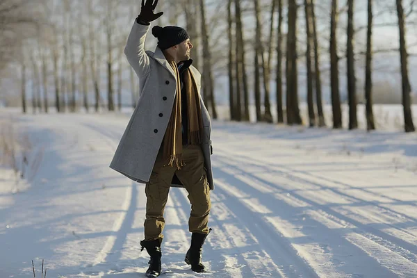 コート 冬のスタイルでファッショナブルな男は 冬の風景 雪の天候 暖かい服を背景に歩きます — ストック写真