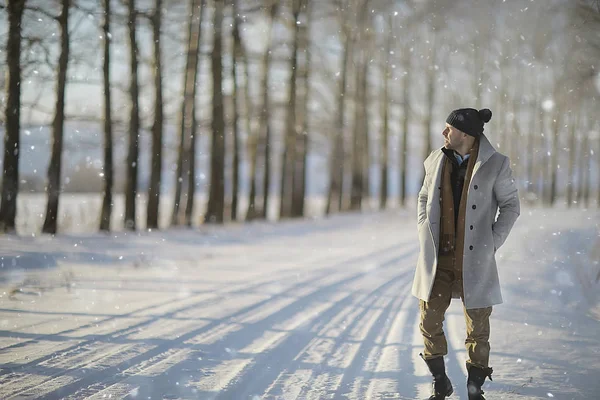 コート 冬のスタイルでファッショナブルな男は 冬の風景 雪の天候 暖かい服を背景に歩きます — ストック写真