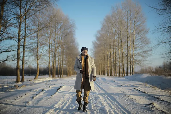 コート 冬のスタイルでファッショナブルな男は 冬の風景 雪の天候 暖かい服を背景に歩きます — ストック写真