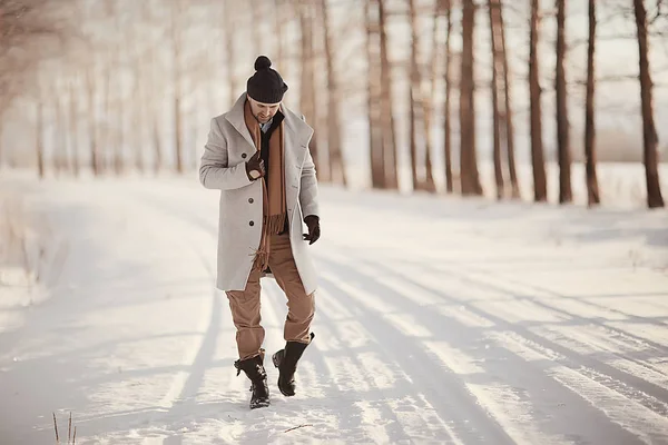 コート 冬のスタイルでファッショナブルな男は 冬の風景 雪の天候 暖かい服を背景に歩きます — ストック写真