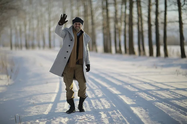 コート 冬のスタイルでファッショナブルな男は 冬の風景 雪の天候 暖かい服を背景に歩きます — ストック写真