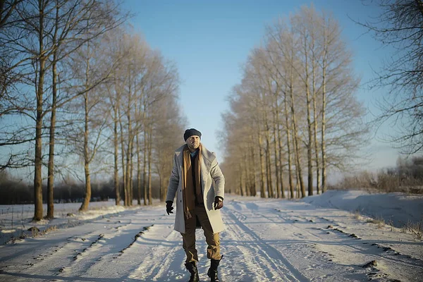 コート 冬のスタイルでファッショナブルな男は 冬の風景 雪の天候 暖かい服を背景に歩きます — ストック写真