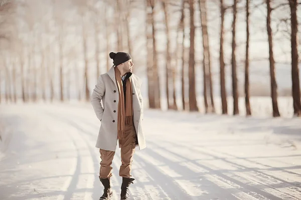 コート 冬のスタイルでファッショナブルな男は 冬の風景 雪の天候 暖かい服を背景に歩きます — ストック写真