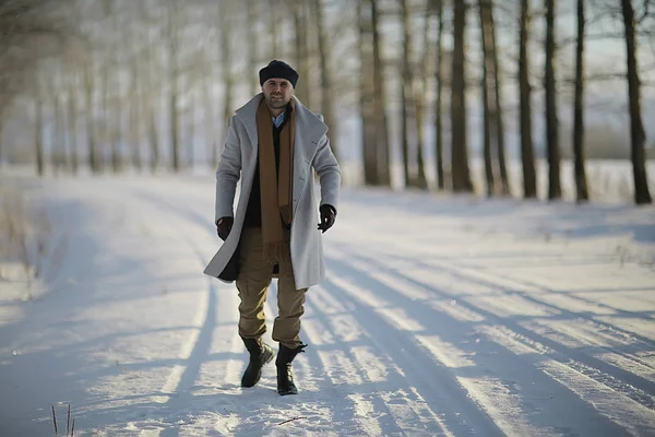 コート 冬のスタイルでファッショナブルな男は 冬の風景 雪の天候 暖かい服を背景に歩きます — ストック写真