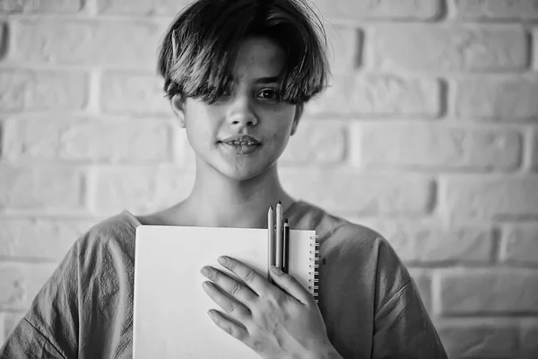 adult girl draws on paper pencils / portrait of a beautiful young female student, art school education, concept of art education