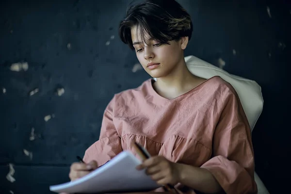 adult girl draws on paper pencils / portrait of a beautiful young female student, art school education, concept of art education