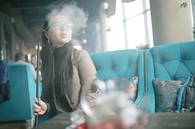 yetişkin kız bir kafede bir nargile sigara / modern iç, sigara, duman, gece kulübü, gün.