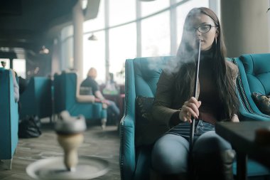 yetişkin kız bir kafede bir nargile sigara / modern iç, sigara, duman, gece kulübü, gün.