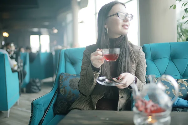 girl in a cafe drinking tea / a modern cafe, a young adult model drinking tea and holding a cup in her hand