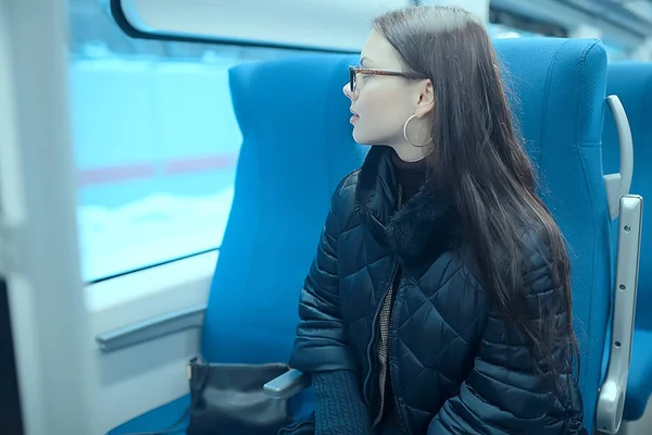 girl sits on a train / winter transport, one adult girl sits by the train window traveling