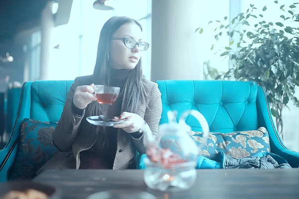 girl in a cafe drinking tea / a modern cafe, a young adult model drinking tea and holding a cup in her hand