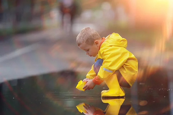 少年は水たまりでボートを遊ぶ 子供の頃 公園で秋のゲーム 散歩中の子供 — ストック写真