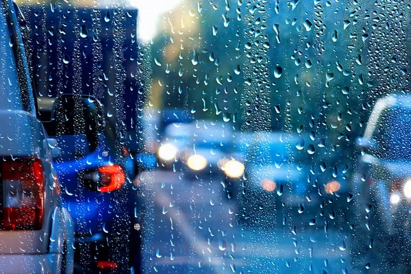 drops on glass auto road rain autumn night / abstract autumn background in the city, auto traffic, romantic trip by car