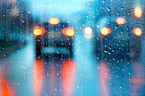 drops on glass auto road rain autumn night / abstract autumn background in the city, auto traffic, romantic trip by car