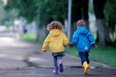çocuklar yağmurluk / yazlık park, yağmur, erkek ve kız kardeşi, çocuk erkek ve kız yürümek koşmak