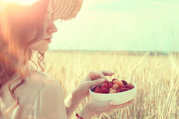 ピクニックフィールドの太陽を食べる女の子のラズベリー 晴れた夏のフィールドでラズベリーを食べる大人の若いモデル 幸せロマンスを楽しむ — ストック写真